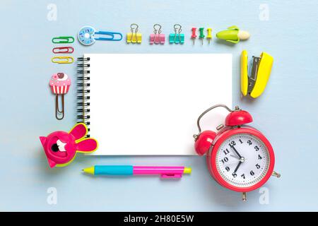 Back to school, education concept. Yellow backpack with school supplies - pens, calculator, markers, stapler, notepad, paper clips isolated on blue ba Stock Photo