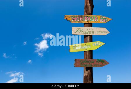 Colorful wooden signs with distances to other cities against a blue sky Stock Photo