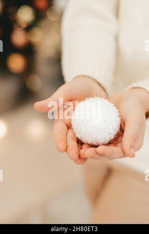 white Christmas tree toy close-up, in the hands of a girl. Vertical frame Stock Photo