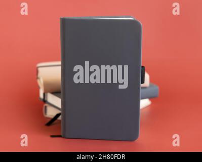 Stack of beige and grey hardcover notebooks isolated on red closeup. Textbook mockup, planner cover with place fot text. Educational, business and org Stock Photo
