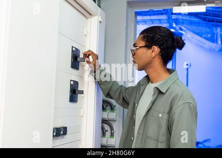 young african american engineer making maintenance of switchboard while working in data center Stock Photo