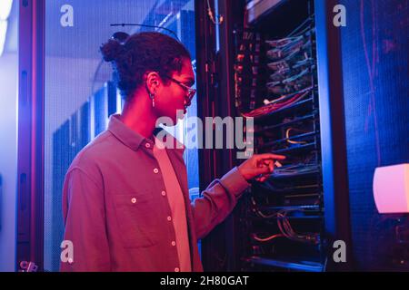african american technician checking wires of server in data center Stock Photo
