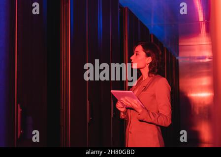 technician with digital tablet checking servers in data center in neon light Stock Photo