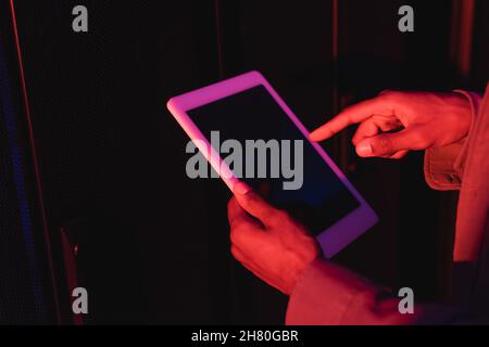 cropped view of african american programmer pointing at mobile phone with blank screen in data center Stock Photo