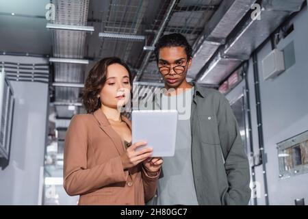 interracial programmers looking at digital tablet while working in data center Stock Photo