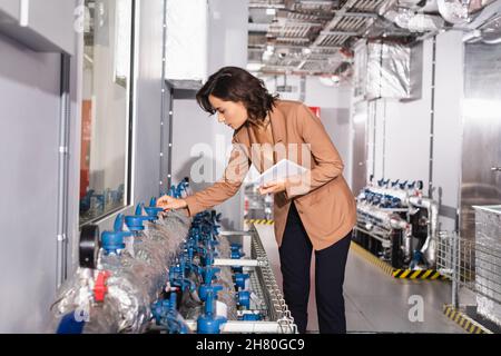 young technician holding digital tablet while checking cooling system of data center Stock Photo