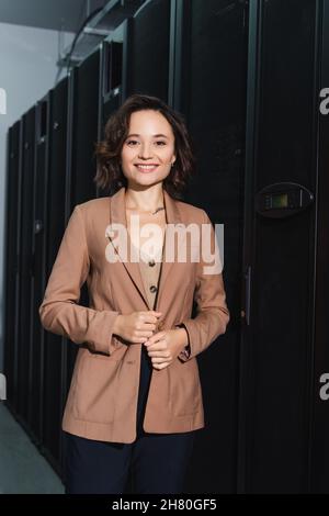 cheerful engineer smiling at camera while standing in data center Stock Photo
