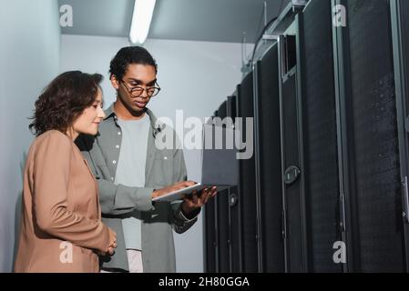 african american programmer showing laptop to colleague while working in data center Stock Photo