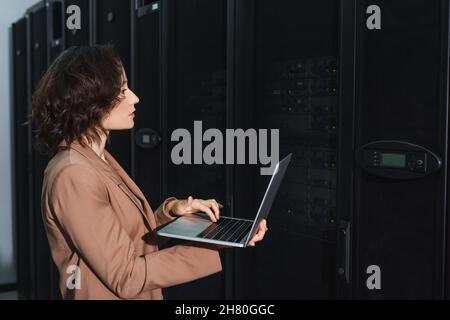 programmer using laptop while checking servers in data center Stock Photo