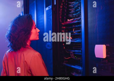 engineer checking server while working in data center in neon light Stock Photo