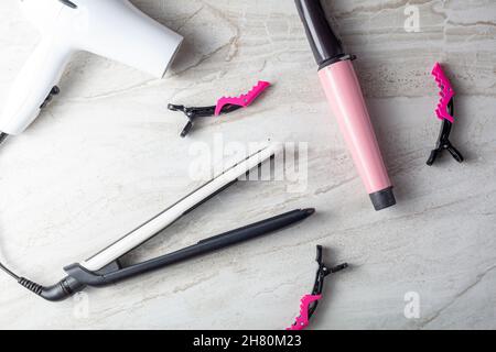 A collection of household tools used for DIY hairdo at home or in salon. The set includes curling and straightening wands, hair dryer and sectioning c Stock Photo