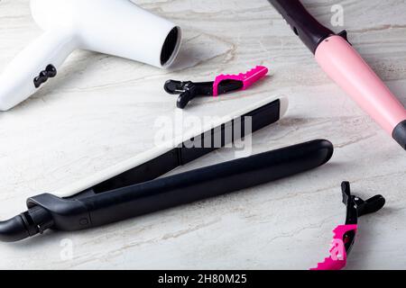 A collection of household tools used for DIY hairdo at home or in salon. The set includes curling and straightening wands, hair dryer and sectioning c Stock Photo