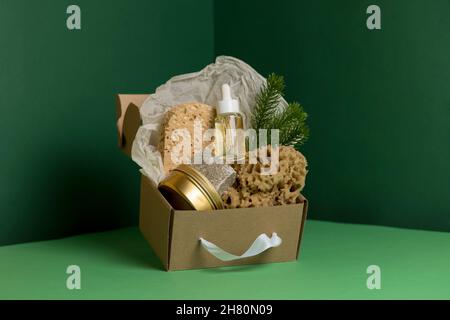 Natural sea sponges, soup, cosmetic bottle with oil in craft box in green corner Stock Photo