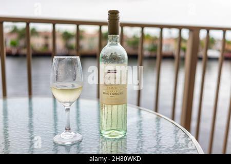 Hollywood, USA - July 13, 2021: Closeup of bottle of Italian Pinot Grigio white wine alcohol drink glass Kirkland brand bought at Costco on glass balc Stock Photo