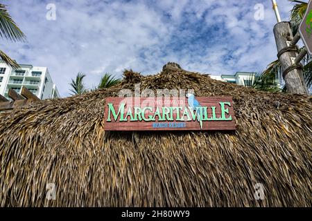 Hollywood, USA - August 4, 2021: North of Miami Beach, Hollywood broadwalk boardwalk in Florida with sign on tiki hut entrance to Margaritaville resta Stock Photo