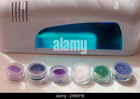 sequins for manicure and uv lamp on a white table. Stock Photo
