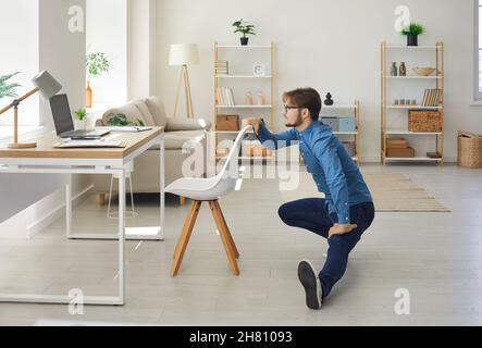 Young businessman combines work and healthy lifestyle doing sports in his home office. Stock Photo