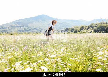 a beautiful woman in a dress running around the field with daisies Stock Photo