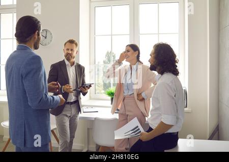 Smiling employees have pleasant conversation discussing work at meeting in office. Stock Photo