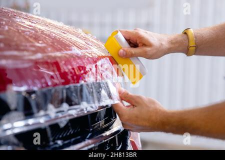 Closeup installing protective transparent vinyl film to protect paint and varnish of car. Stock Photo