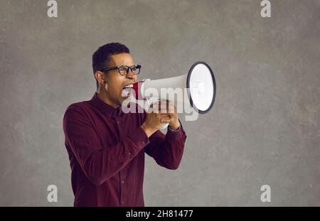An excited crazy angry young African American man loudly shouting in a megaphone Stock Photo