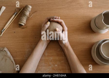 The stage of creating a pot from clay. Female hands making a hole in a piece of clay. craft work and creative craft concept. Stock Photo