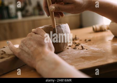 Author's decoration and production of earthenware pottery. Handmade ceramic tableware carving with special tools. hands in clay. Stock Photo