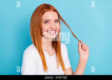 Photo of satisfied friendly orange hair girl arm fingers hold play with tail isolated on blue color background Stock Photo