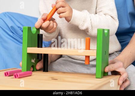 Close up view of a Therapist doing development activities with a little boy. Boy with cerebral palsy having rehabilitation, learning. Training in medical care center. High quality photo. Stock Photo