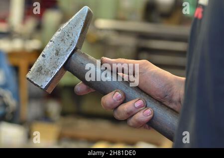 A dirty hand holds a hammer. Stock Photo