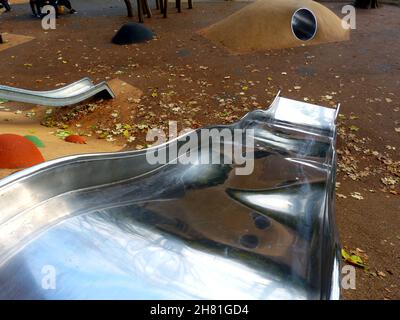 playground in public park. colorful orange, yellow and green rubber safety flooring. playful semi spheres. shiny stainless steel slide. with bumps. Stock Photo