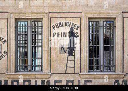 Old Painted Wall Advert or Publicity with Signwriter on Ladder on Facade of Former Printers in the Old Town Avignon Provence France Stock Photo