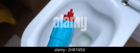 Cleaner in yellow rubber gloves pouring detergent under rim of toilet closeup Stock Photo