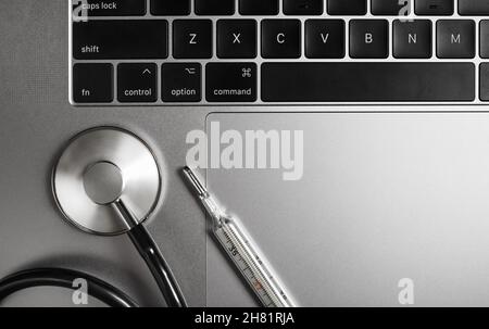 Stethoscope and thermometer on laptop keyboard. Flat lay. Stock Photo