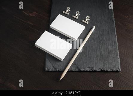 Two stacks of blank business cards, pencil and metal clamps on stone board background. Copy space. Stock Photo