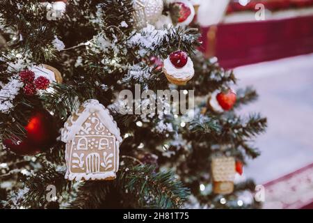 Christmas tree decorated with toys. Gingerbread house hanging on a branch. New year decoration Stock Photo