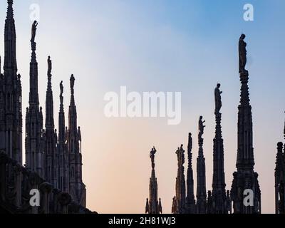 Milan, Lombardy, Italy.  December 2019.  Some of the 96 giant stone statues on the gargoyles of Milan's cathedral at sunset. Stock Photo