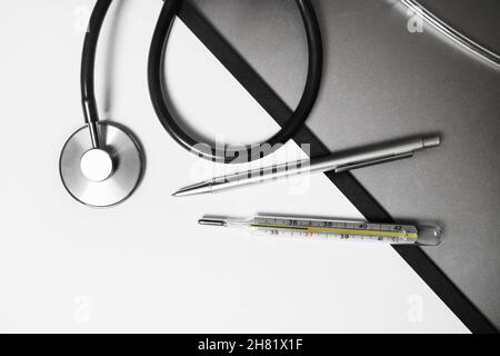 Medical stethoscope, thermometer and pen. Flat lay. Stock Photo