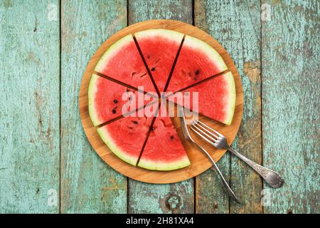 Healthy low calorie vegan snack. Fresh watermelon served like pizza on round bamboo board above view Stock Photo
