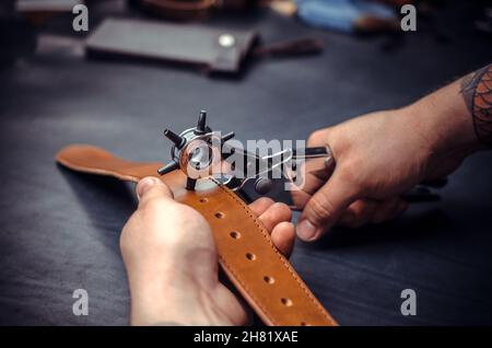 Craftsman performs leather working for a new product in his tanning shop Stock Photo