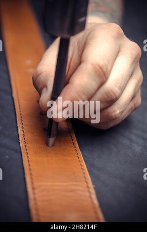 Leather Worker performing leatherwork on a new product piece in the work area Stock Photo