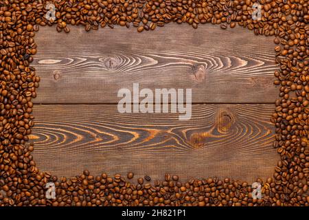 rectangular frame of many roasted coffee beans on brown wooden surface Stock Photo