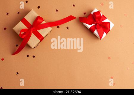 Brown and white gift boxes with tied red satin ribbon bows on brown background with red stars shapes.Christmas Holidays and present concept flat lay w Stock Photo
