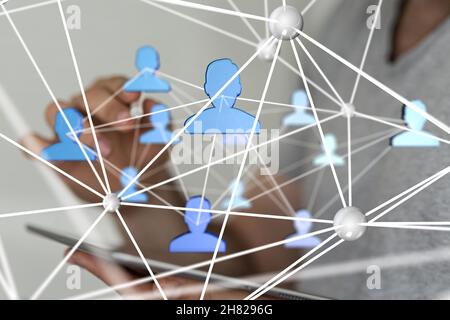 Hologram of a network of people working as a team, projecting from a woman's tablet Stock Photo