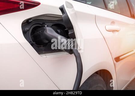 Power supply plugged into an electric vehicle Stock Photo