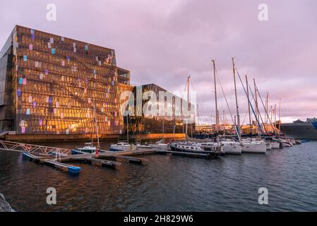 Reykjavik, Iceland - July 09, 2020: View from the harbour of Harpa concert hall lit by midnight sun in summer. Moored sailing boats are in foreground. Stock Photo