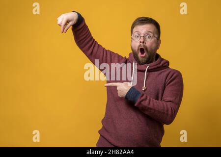 Shocked man showing fingers as if he is holding or picking up an invisible object and points at it with forefinger. Copy space.  Stock Photo