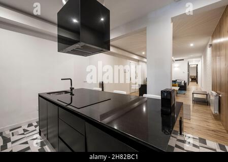 Black marble kitchen island with hob and hood in a vacation rental apartment Stock Photo