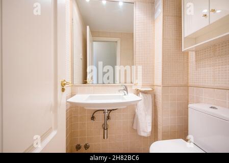 Bathroom with large sink for hand washing and light sand tile and built-in wall mirror Stock Photo