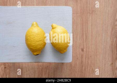 Pair of yellow lemons filled with juice on a blue table Stock Photo